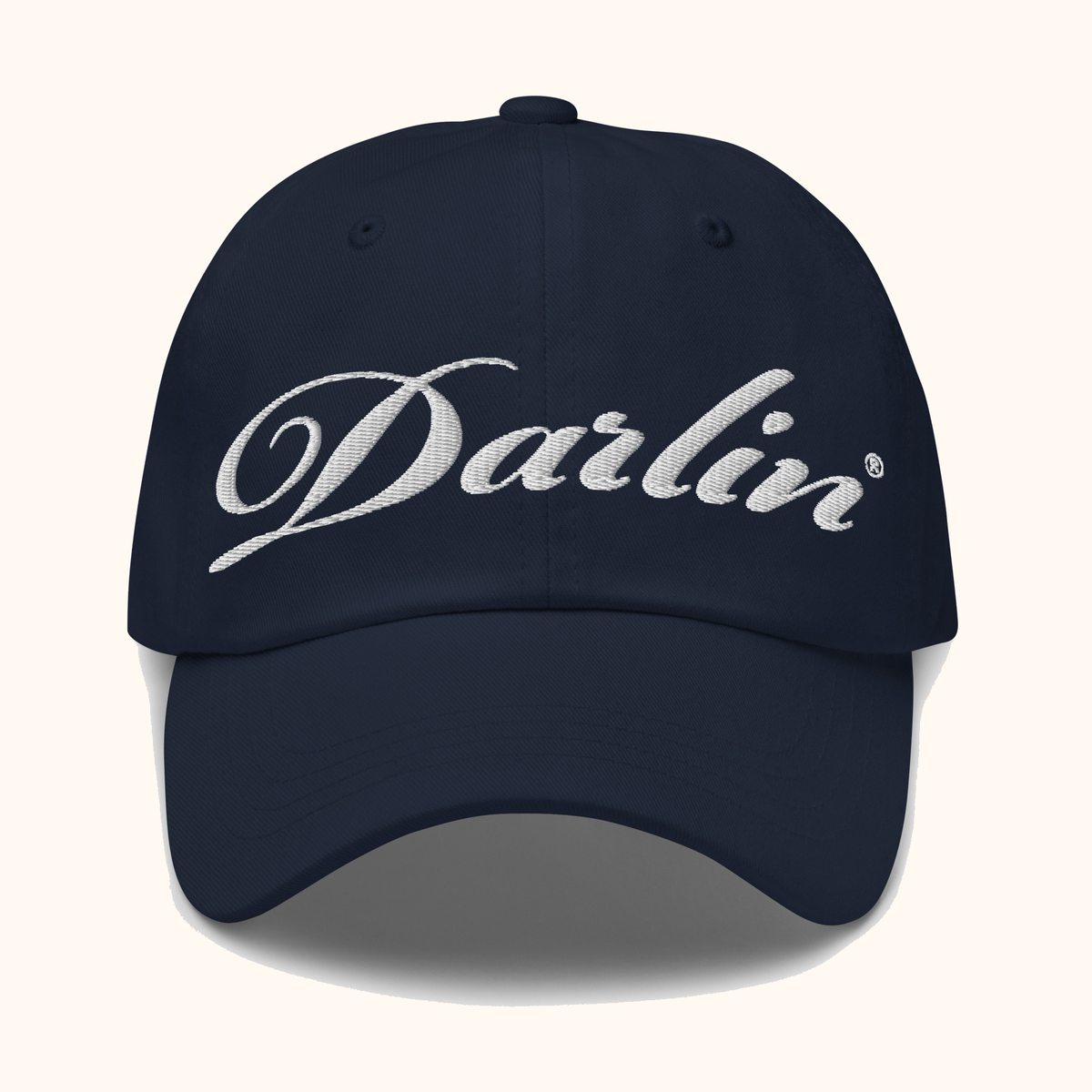 Front view of DARLIN original script navy hat with white embroidery on a warm ivory background