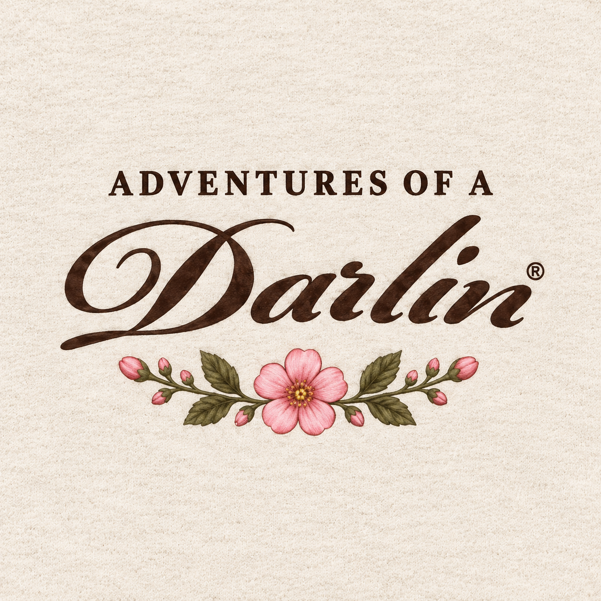 Close-up of Adventures of a DARLIN® script and pink primrose design on cream kids crewneck