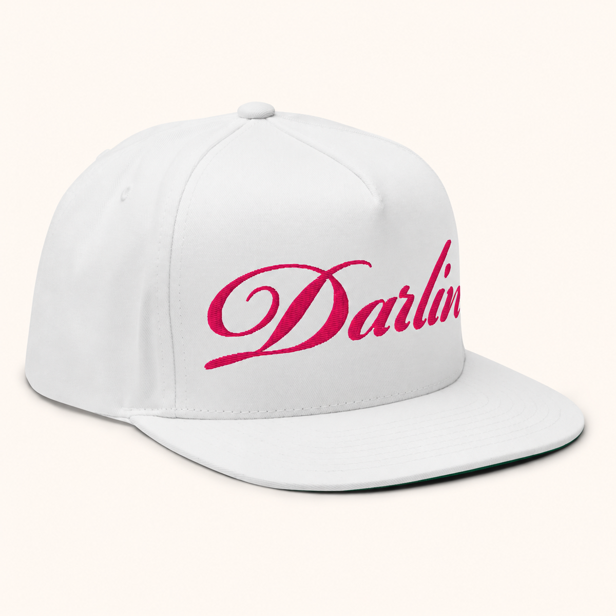 Right-front view of the DARLIN® Fuchsia Script White Snapback Hat showing fuchsia script embroidery, white stitching and a flat bill on an ivory background.