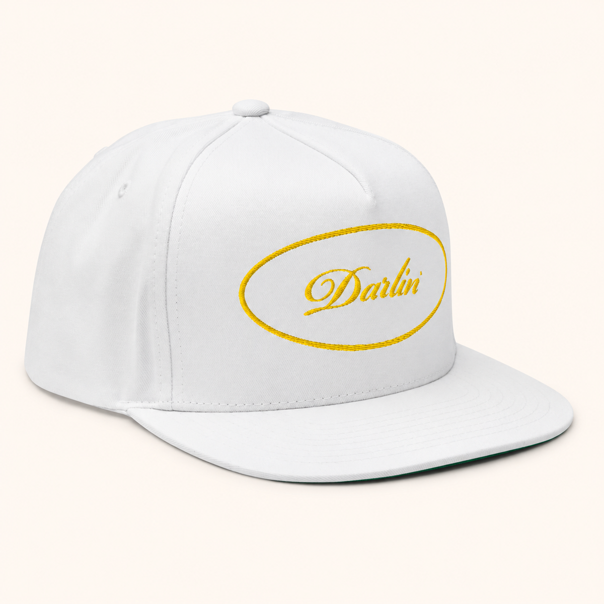 DARLIN® Gold Oval Snapback Hat in white with gold script embroidery – angled view