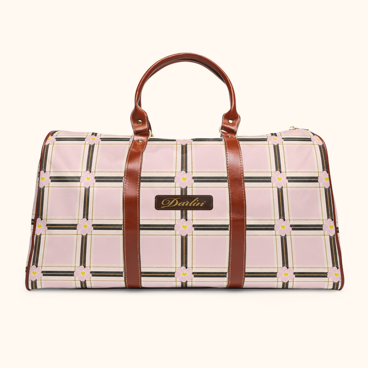 Front view of the DARLIN® Primrose Plaid Weekender with pink floral plaid, brown handles, and a chocolate-and-gold script emblem on a warm ivory background.