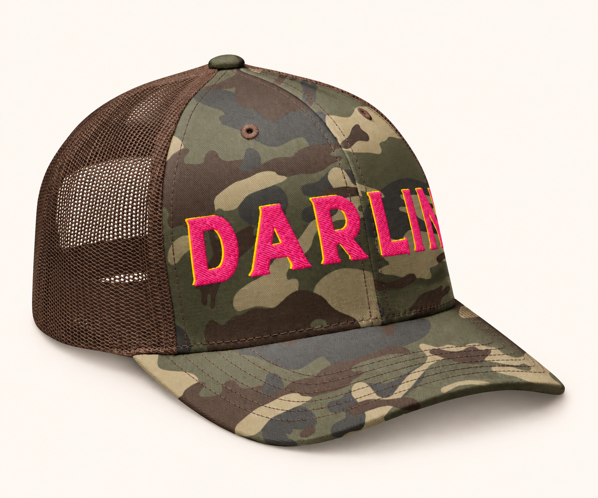 Angled view of DARLIN® pink embroidery camo trucker hat with pink and yellow 3D puff embroidery and brown mesh back