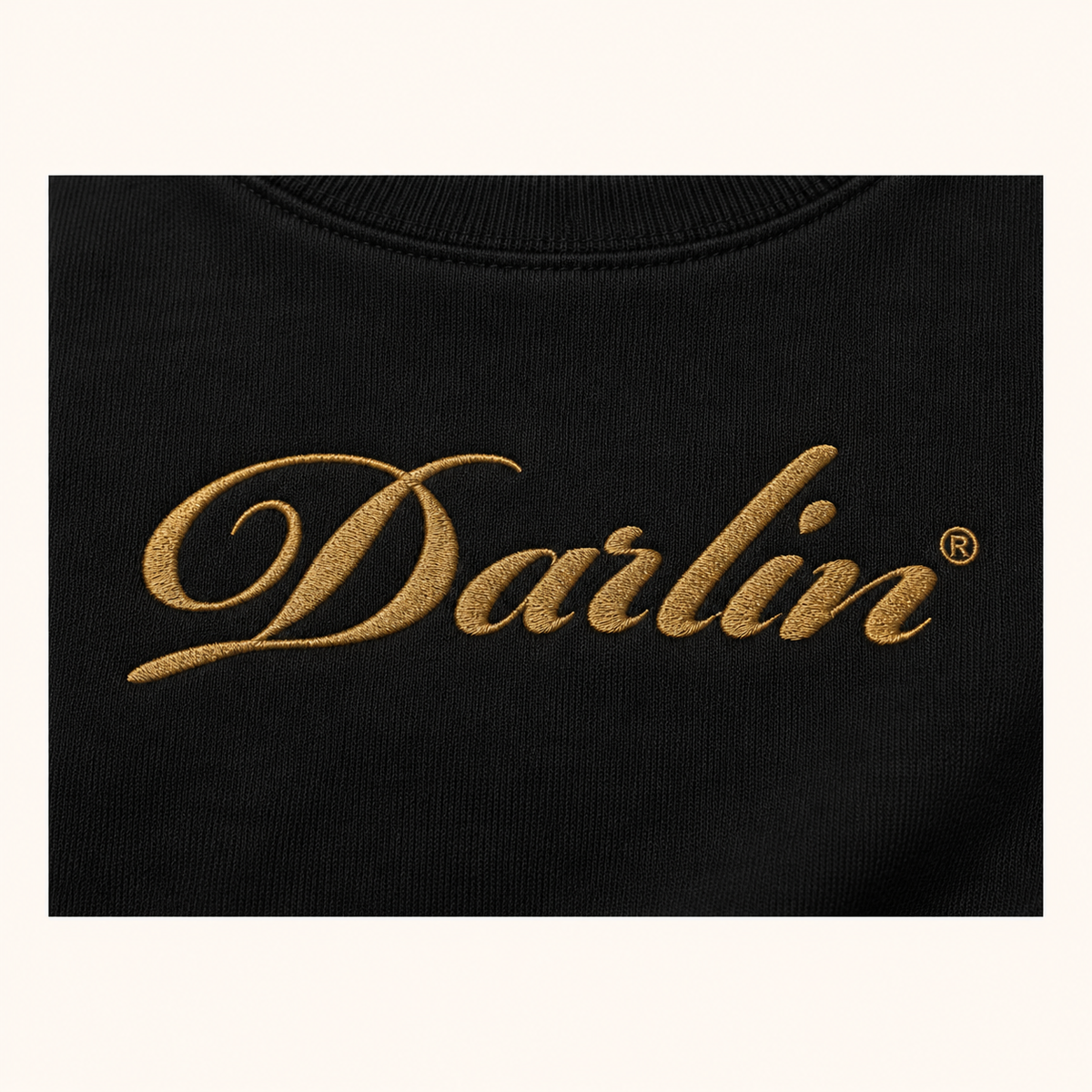 Close-up of Vintage Gold DARLIN® script embroidery on black crewneck sweatshirt