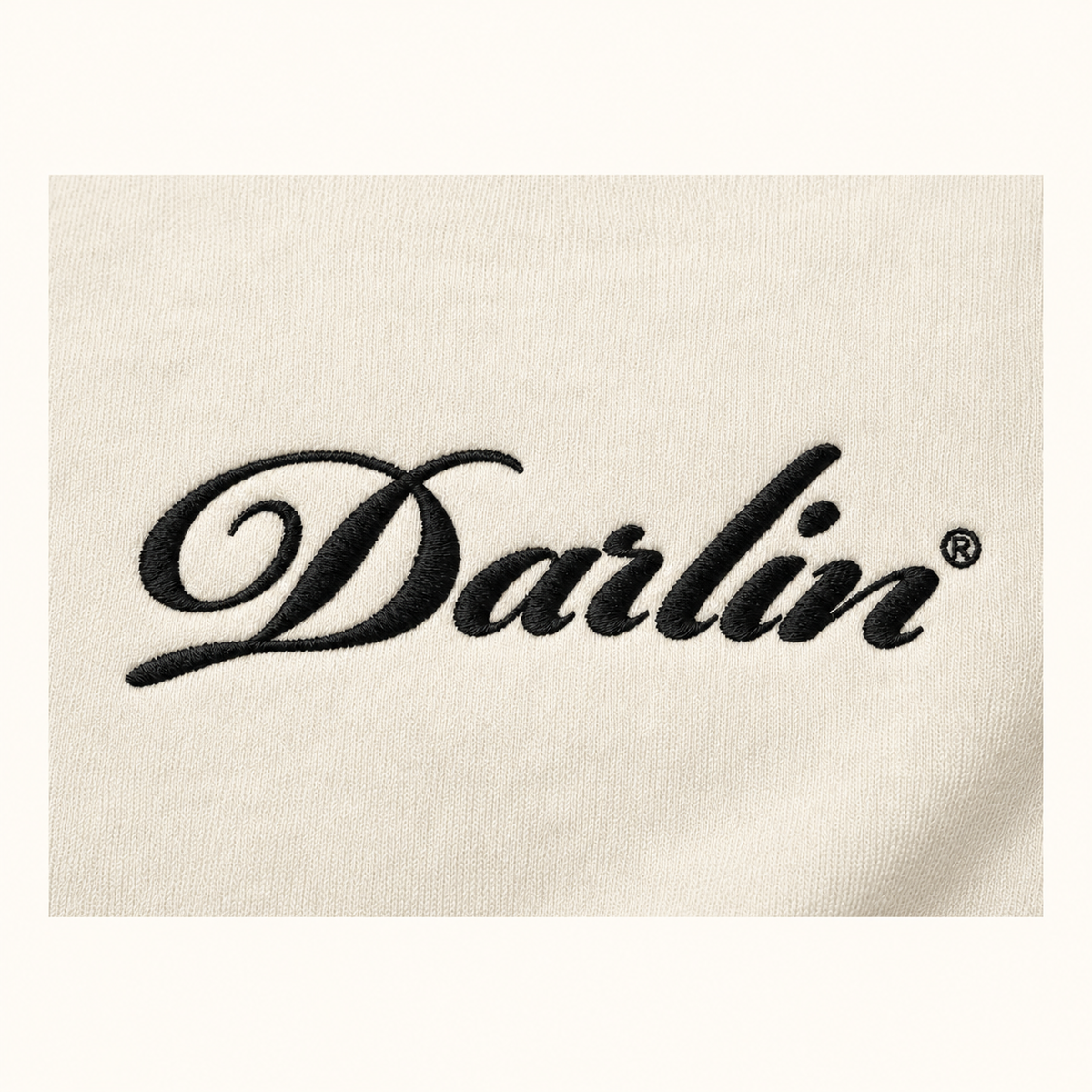 Close-up of black DARLIN® script embroidery on cream crewneck sweatshirt