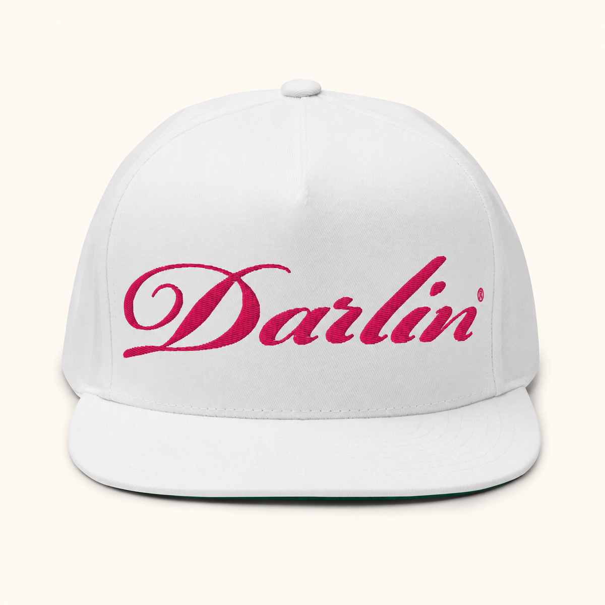 Front view of the DARLIN® Fuchsia Script White Snapback Hat with fuchsia script embroidery and a flat bill on an ivory background.