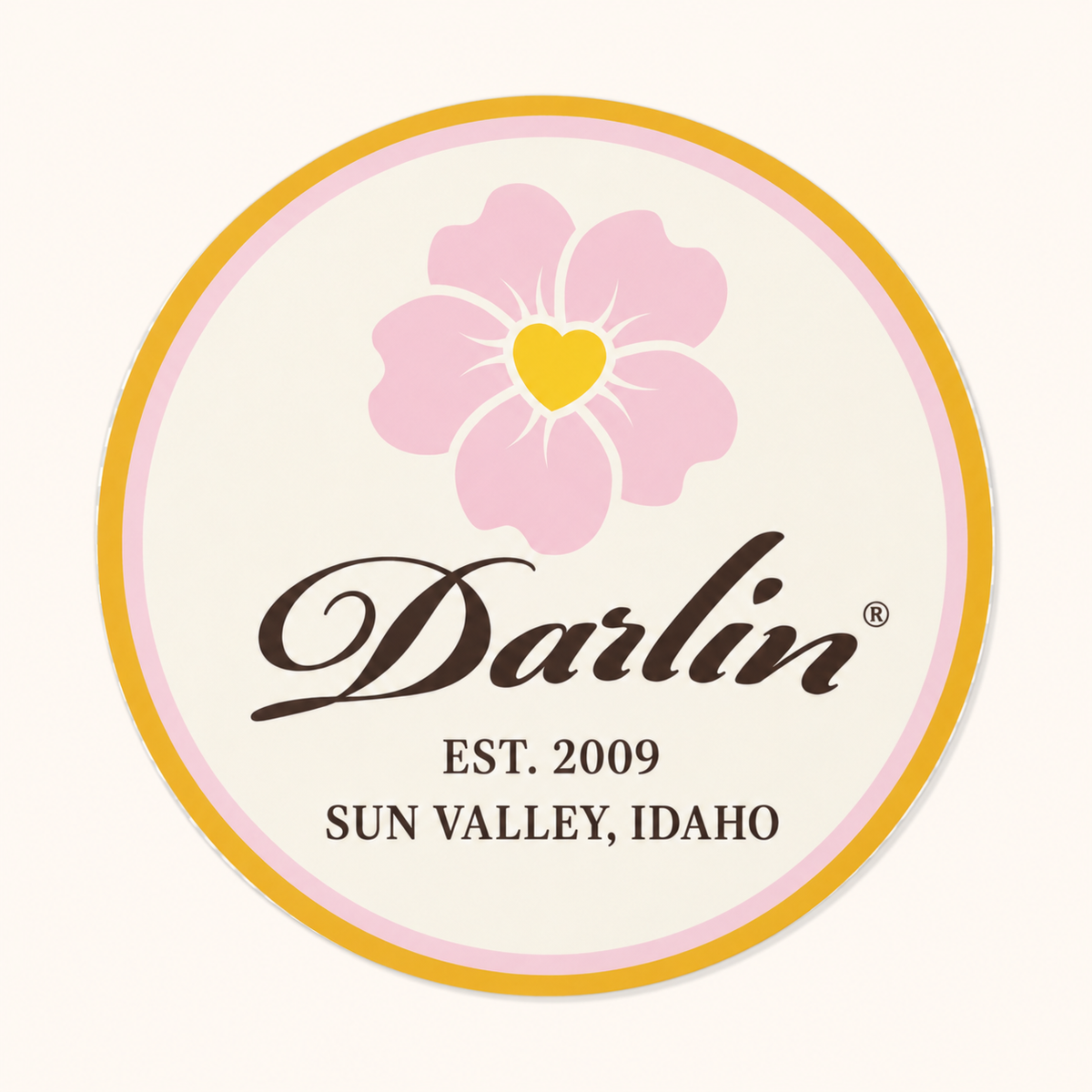 Round DARLIN® Script Heritage Sticker with a pink flower, chocolate script, yellow and pink borders, and “EST. 2009 · SUN VALLEY, IDAHO” on an ivory background.